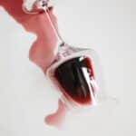 red wine in a glass that has spilt with white background